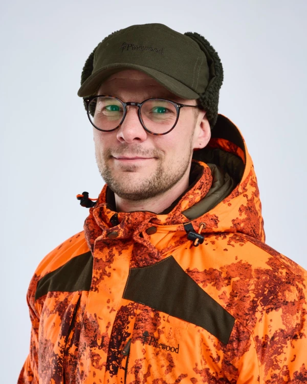 Zielona czapka Pinewood Smaland Teddy Winter 1219 na modelu z nausznikami zapiętymi nad głową
