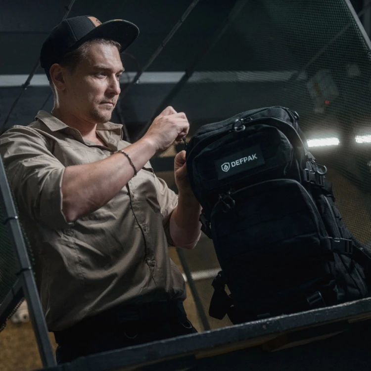 Czarny plecak Defpak Ranger 36 l – użytkownik otwierający plecak