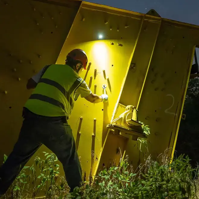 Latarka Olight Perun 3 Black oświetlająca miejsce pracy przy metalowej konstrukcji