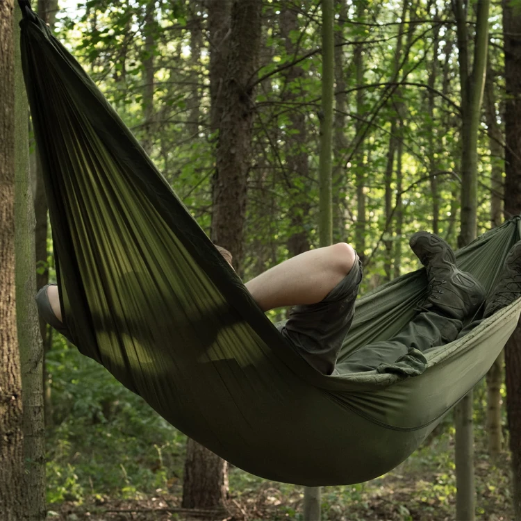 Hamak Badger Outdoor Forest Olive rozwieszony w lesie podczas biwaku